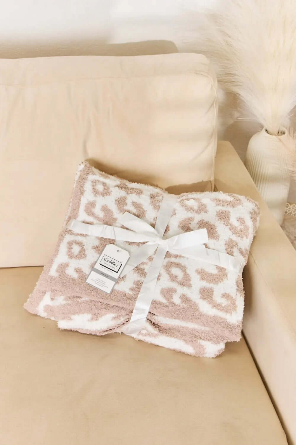Cuddley Leopard Decorative Throw Blanket folded on a couch, showcasing its soft texture and stylish leopard print design.