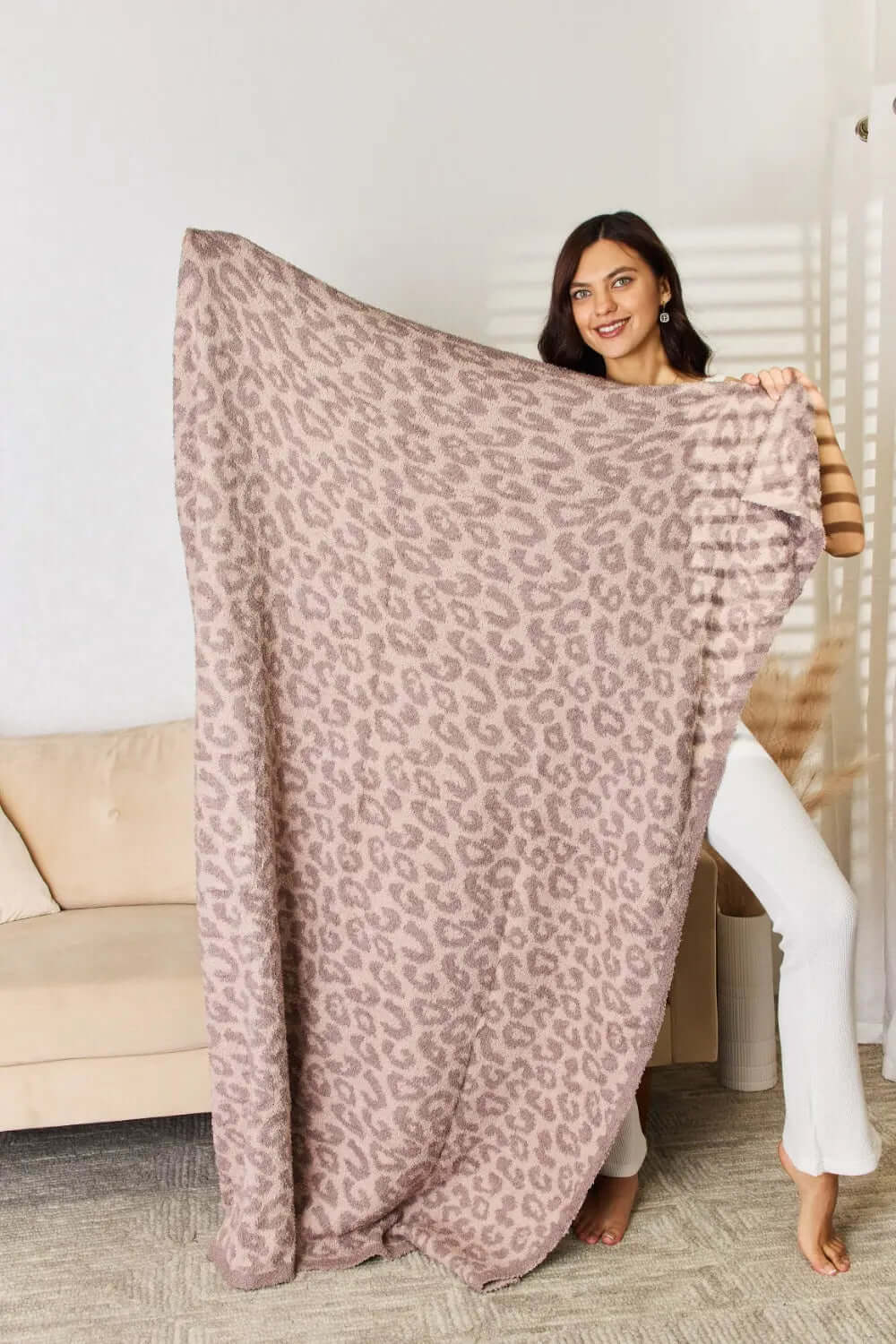 Model showcasing the Cuddley Leopard Decorative Throw Blanket in a cozy setting, highlighting its soft material and stylish leopard print.