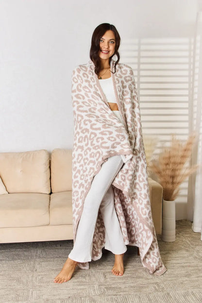 Model draped in a Cuddley Leopard Decorative Throw Blanket, showcasing its cozy and stylish design in a bright living room.