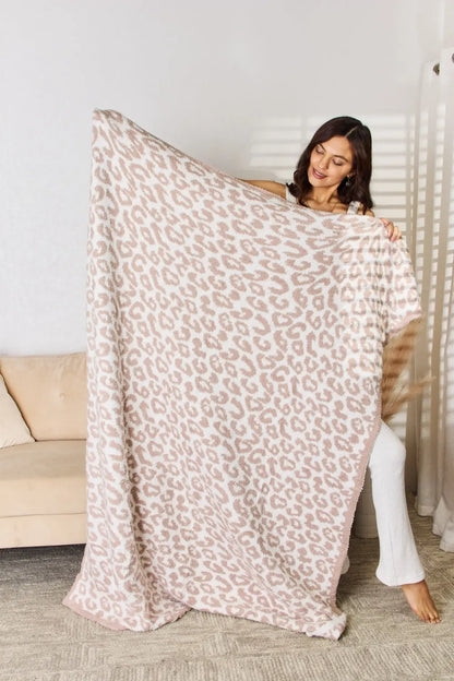 Woman holding a Cuddley Leopard Decorative Throw Blanket showcasing its plush leopard print design in a cozy setting.