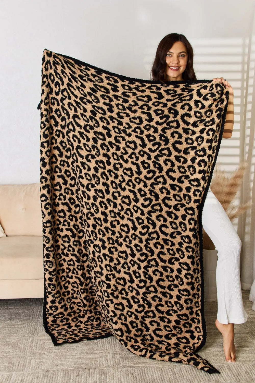 Model showcasing the Cuddley Leopard Decorative Throw Blanket with vibrant leopard print, perfect for cozy decor.