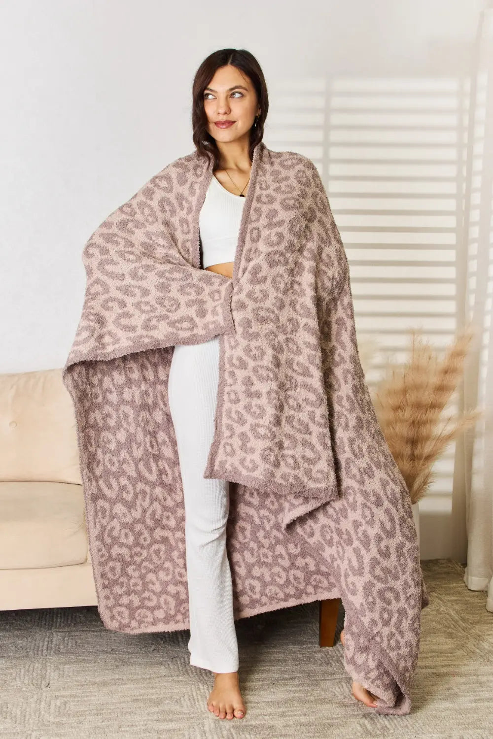 Woman draped in a Cuddley Leopard Decorative Throw Blanket, showcasing its plush leopard print design.